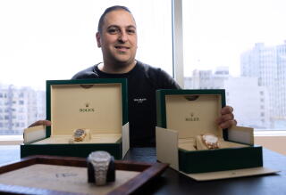 A man poses with two boxes of Rolex watches.