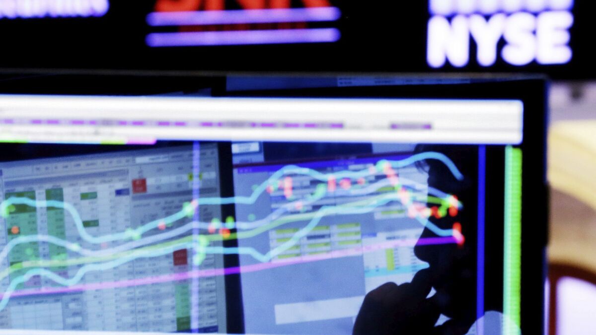 A specialist is silhouetted on a screen at his post on the floor of the New York Stock Exchange.