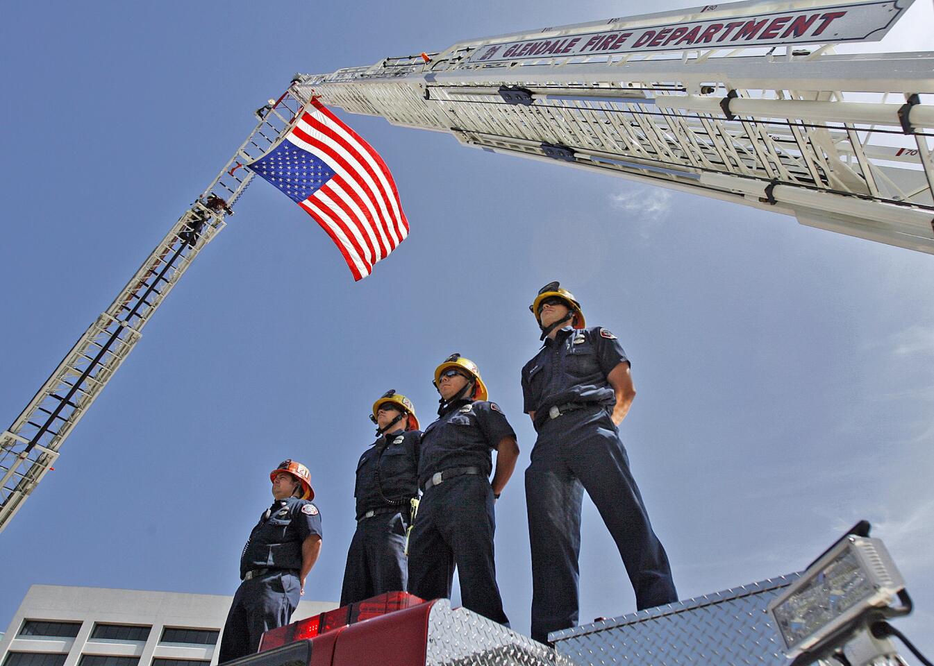 Glendale firemen from Engine 21 stand at attention atop their fire truck on Central Avenue in Gledale to pay their respect to fallen Los Angeles Fire Department Captain David Bailey on Friday, April 6, 2012.