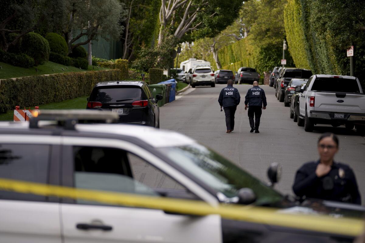 Authorities walk on a street near Sean "Diddy" Combs' L.A. mansion during a raid on March 25.