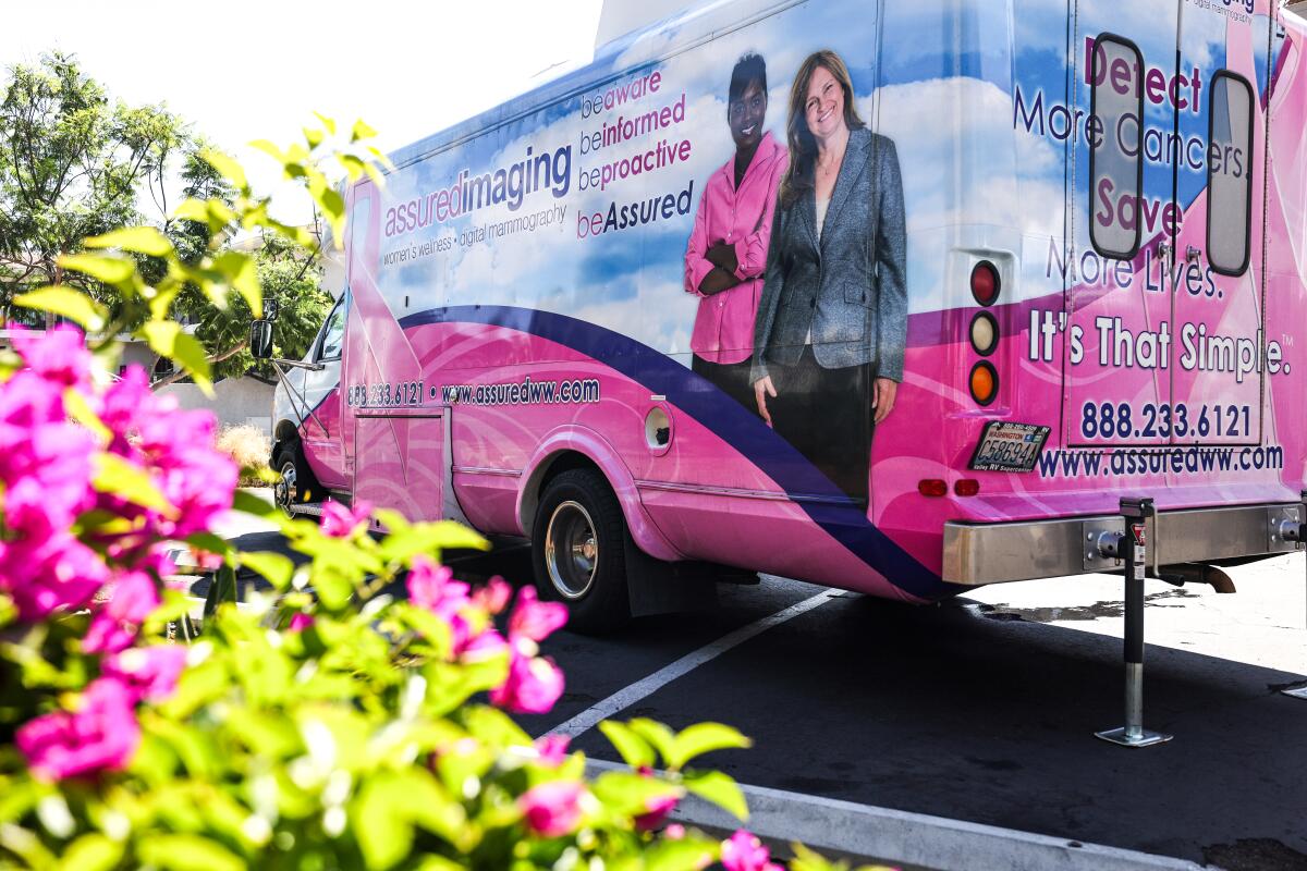 une camionnette de clinique mobile se trouve dans un parking à côté d'un buisson floral