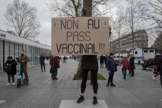 Demonstrator holds a placard that reads 'No to vaccine pass' in opposition to vaccine pass and vaccinations to protect against COVID-19 during a rally in Paris, France, Saturday, Jan. 22, 2022. (AP Photo/Rafael Yaghobzadeh)