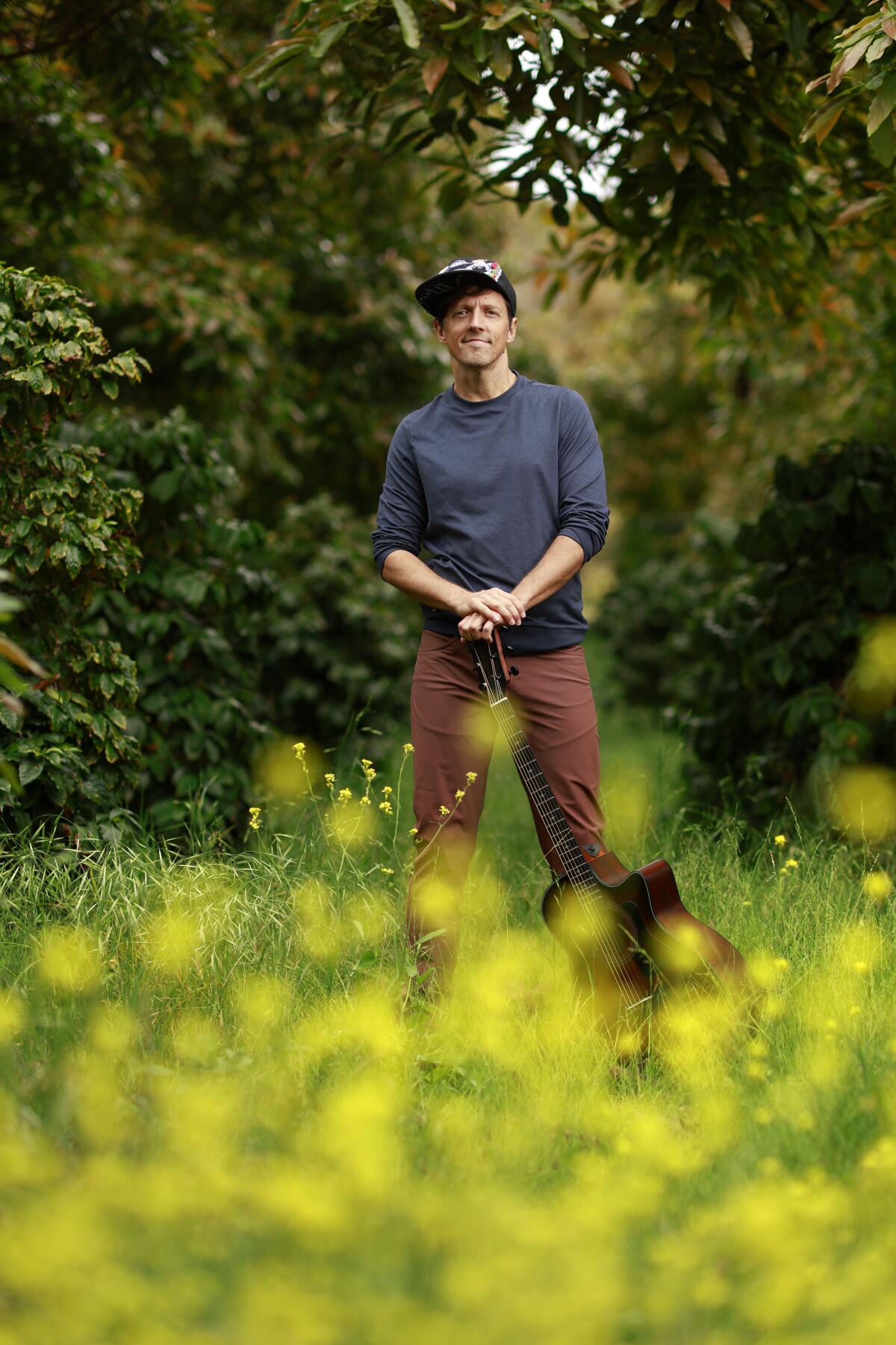Jason Mraz stands near his North County farm, where he grows avocados and coffee beans.