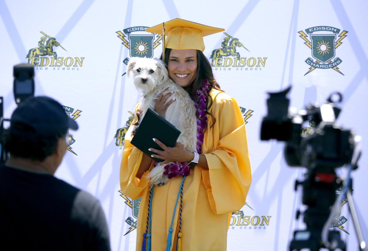 Edison High School graduate Kirstin Bui holds Bailee during Thursday's drive-through graduation ceremony.