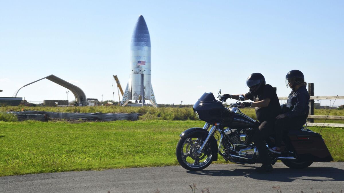 A motorcyclist rides near the SpaceX prototype Starship hopper vehicle at Boca Chica Beach, Texas, on Jan. 12.