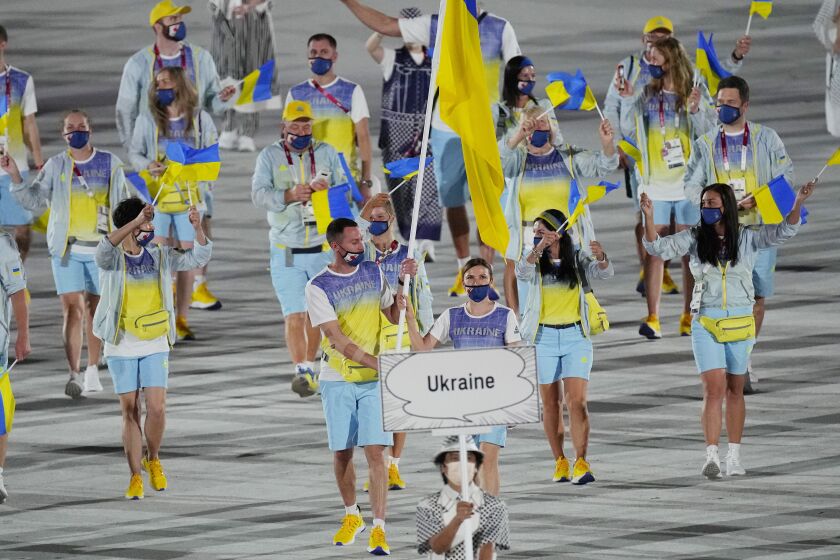 FILE - Olena Kostevych and Bogdan Nikishin, of Ukraine, carry their country's flag during the opening ceremony in the Olympic Stadium at the 2020 Summer Olympics, on July 23, 2021, in Tokyo, Japan. Ukraine has stepped up efforts to lobby international sports leaders against Russian participation in next year’s Paris Olympics as indications mount that the games could see the biggest boycott since the Cold War. (AP Photo/David J. Phillip, File)