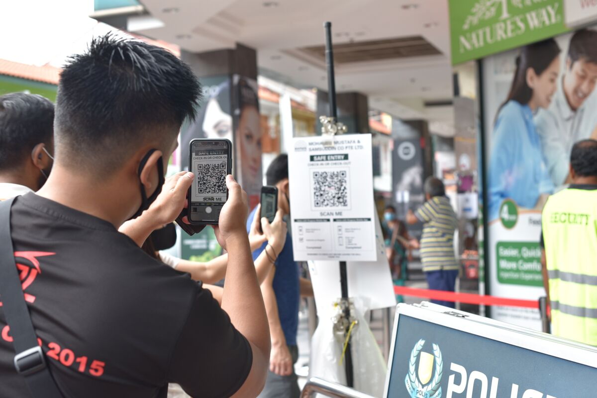 A man scans a QR code to record his entry at a shopping center in Singapore.