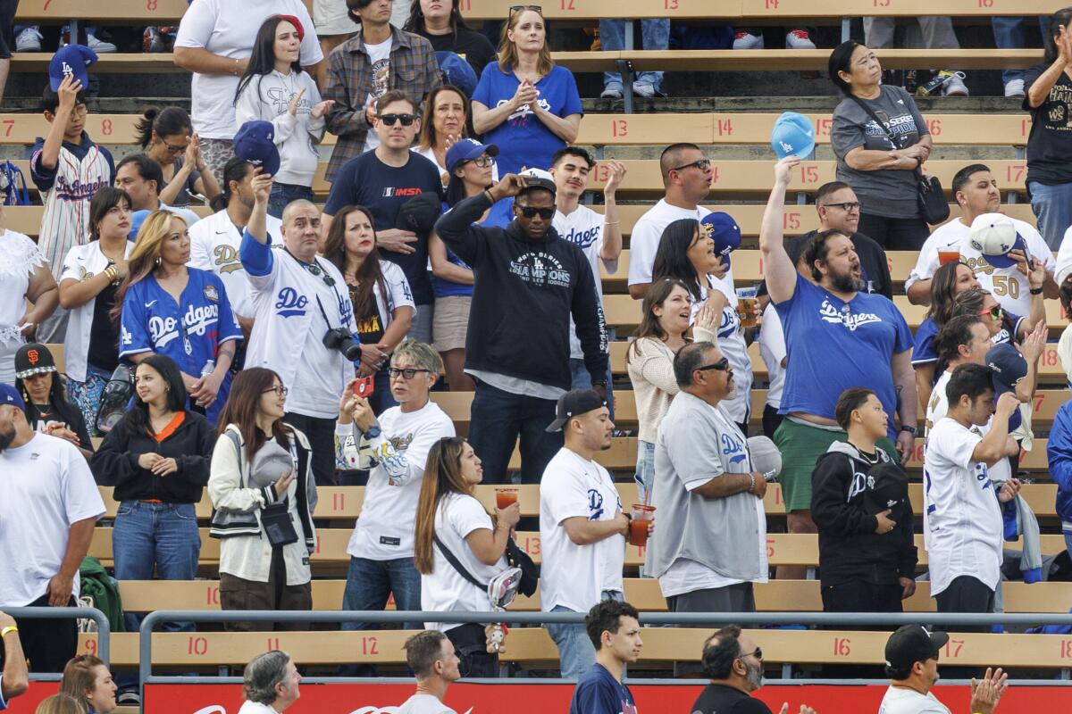 Dodgers fans stand and some tip their caps after singer and social media personality Nezza sang the national anthem.