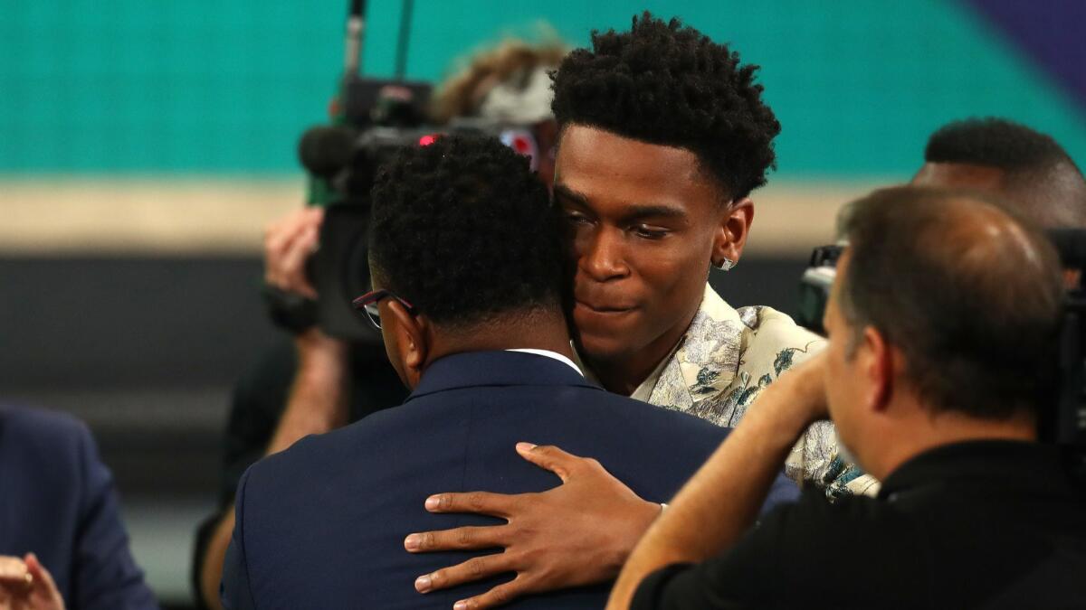 Shai Gilgeous-Alexander receives a congratulatory hug after getting selected 11th overall in the NBA draft on Thursday night.