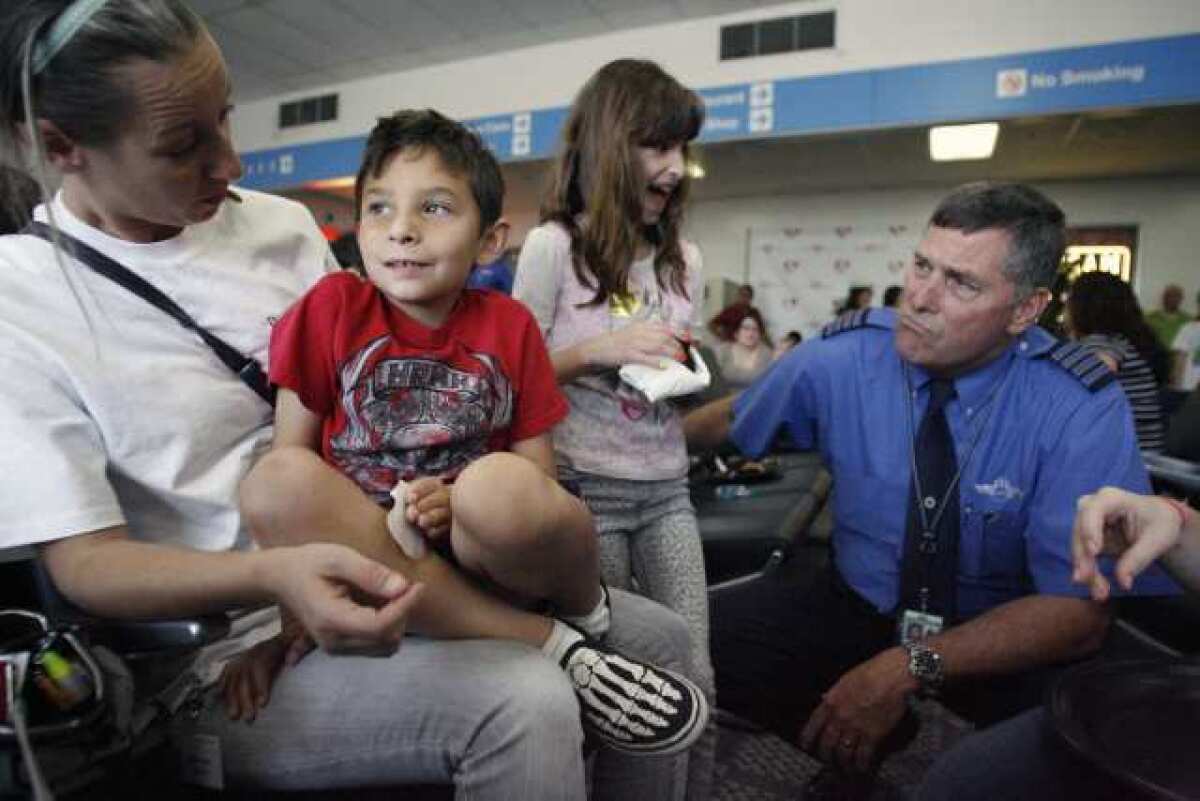 Clinical supervisor Taeja Klug, from far left, gets Jacob Sanchez, 7, to respond to JetBlue chief pilot James Daulton, far right, during Jet Blue, Pacific Child and Family and TSA's "Wings for Autism" program, which took place at Bob Hope Airport in Burbank on Saturday, May 4, 2013. "When you have events for kids with autism like this, it brings the anxiety down," Jennifer Slater-Sanchez said. Jennifer is the mother of Jacob who was diagnosed with autism as a three-year-old.
