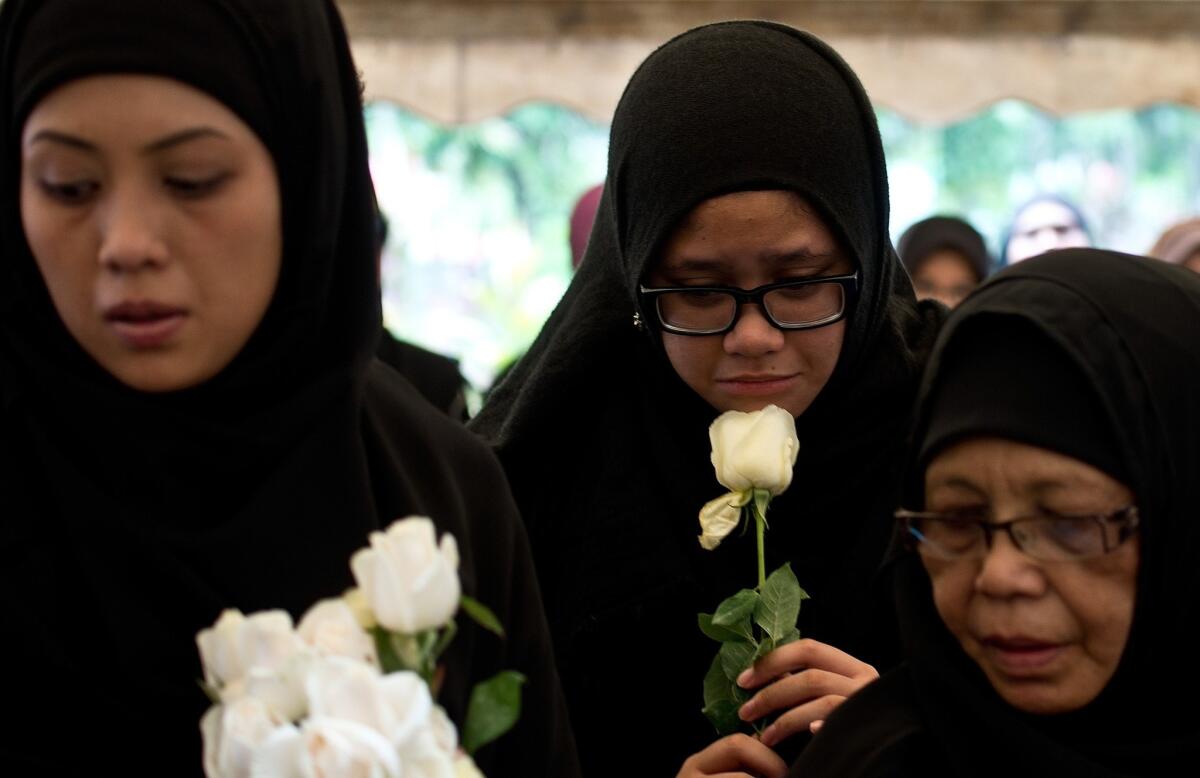 Nur Diyana Yazeera, daughter of Malaysia Airlines chief stewardess Dora Shahila Kassim, holds a white rose during her mother's burial ceremony in Kuala Lumpur.