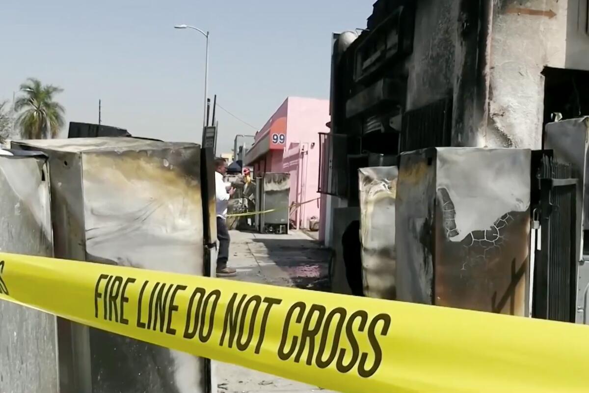 Fire tape that says Fire Line Do Not Cross in front of a burned-out storefront