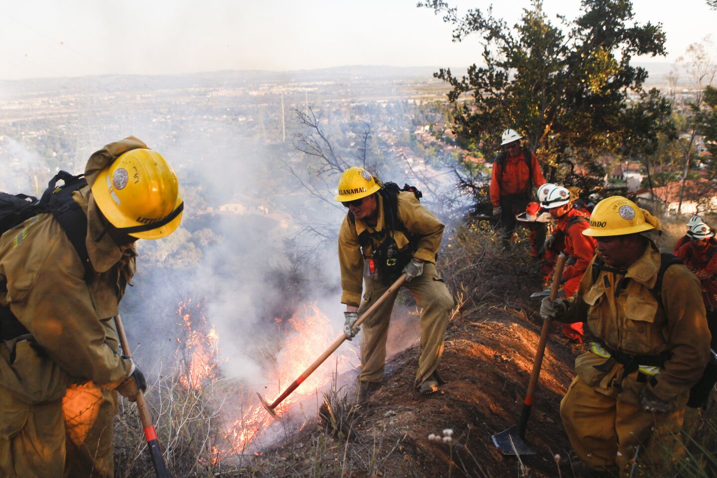 Los Angeles County firefighters work with prison crews to put out hot spots in the Fish fire burning in the hills above Duarte on Monday.