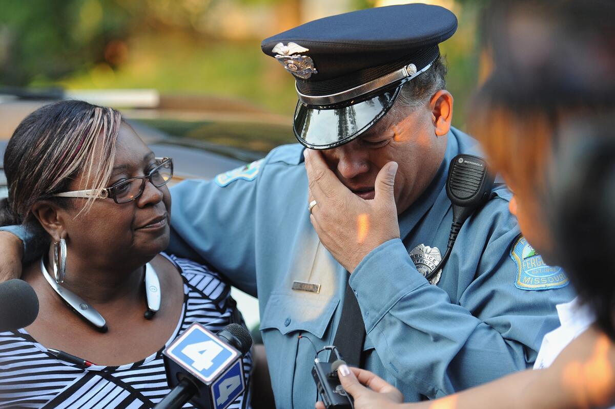 A Ferguson police officer is overcome with emotion during a candlelight vigil held in honor of Jamyla Bolden, 9, who was shot Aug. 18 as she did her homework.