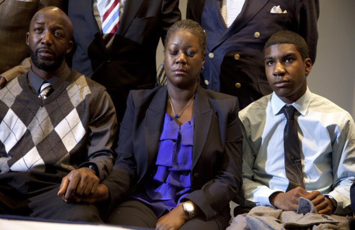 Trayvon Martin's parents, Tracy Martin, left, and Sybrina Fulton, and his brother Jahvaris Fulton watch a news conference where prosecutor Angela Corey announced a second-degree murder charge against George Zimmerman.