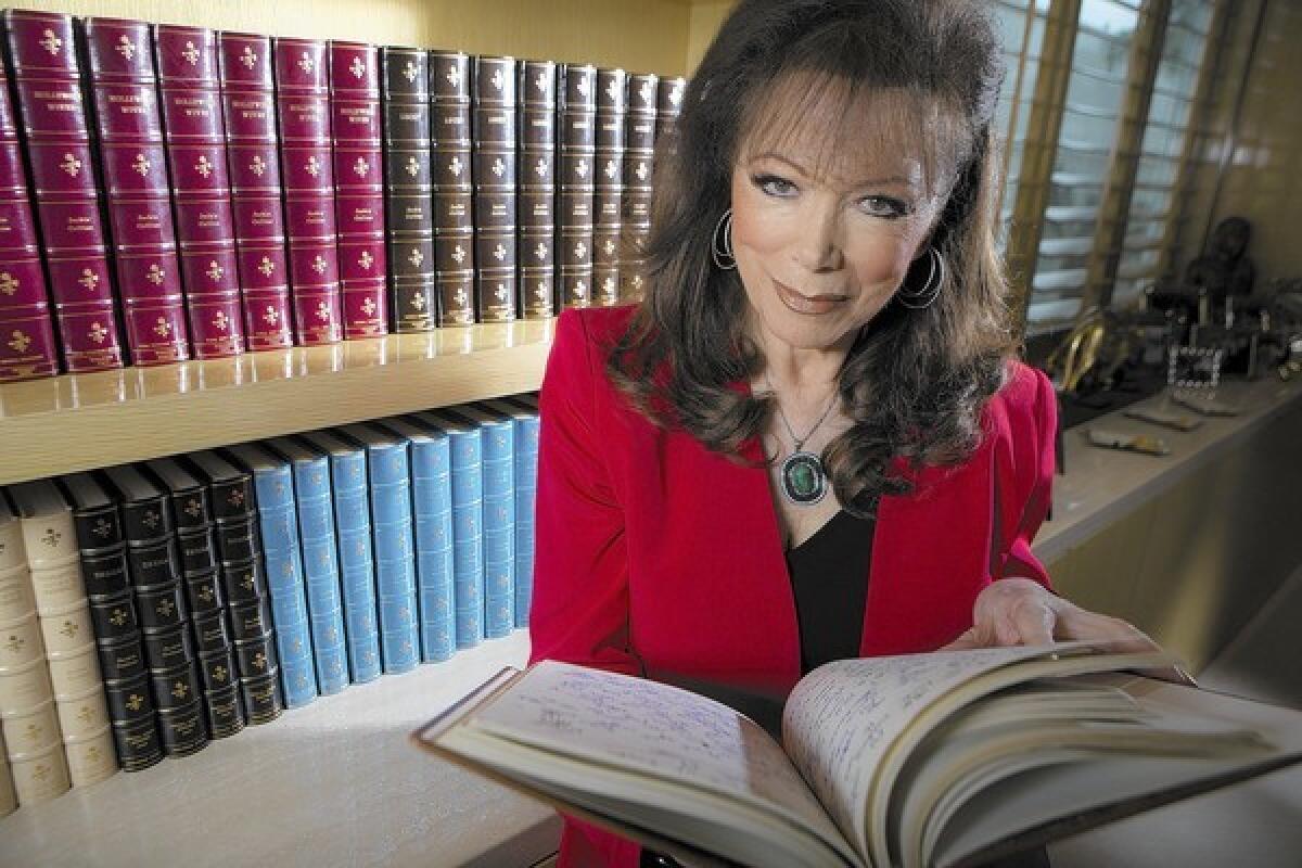 Author Jackie Collins holds one of dozens of bound, handwritten manuscripts in her library