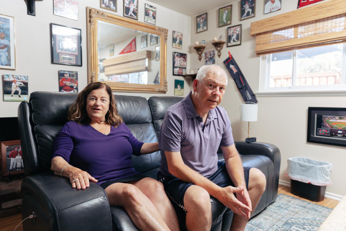 A man and a woman sit on a couch in their living room.