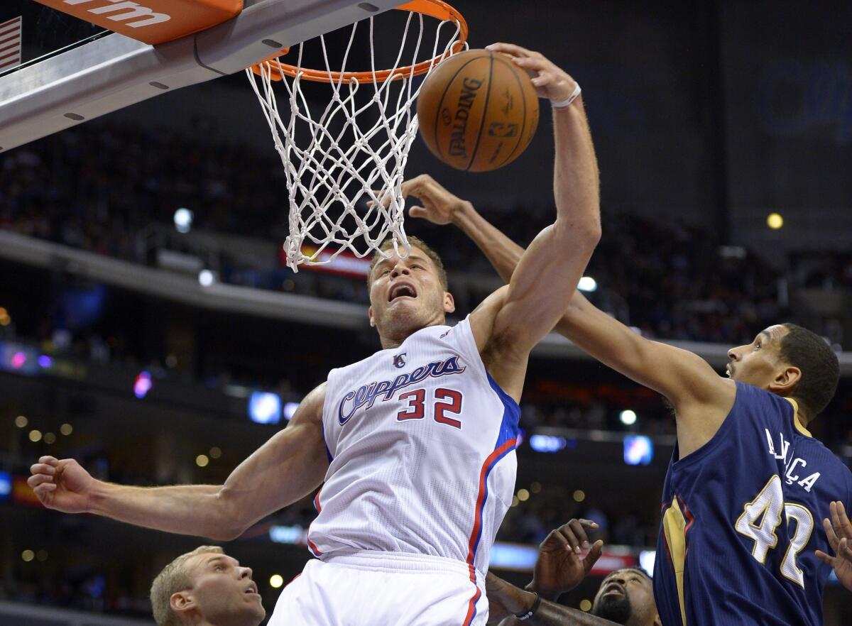 Blake Griffin grabs a rebound away from New Orleans center Alexis Ajinca during the Clippers' 108-76 victory Saturday night at Staples Center.