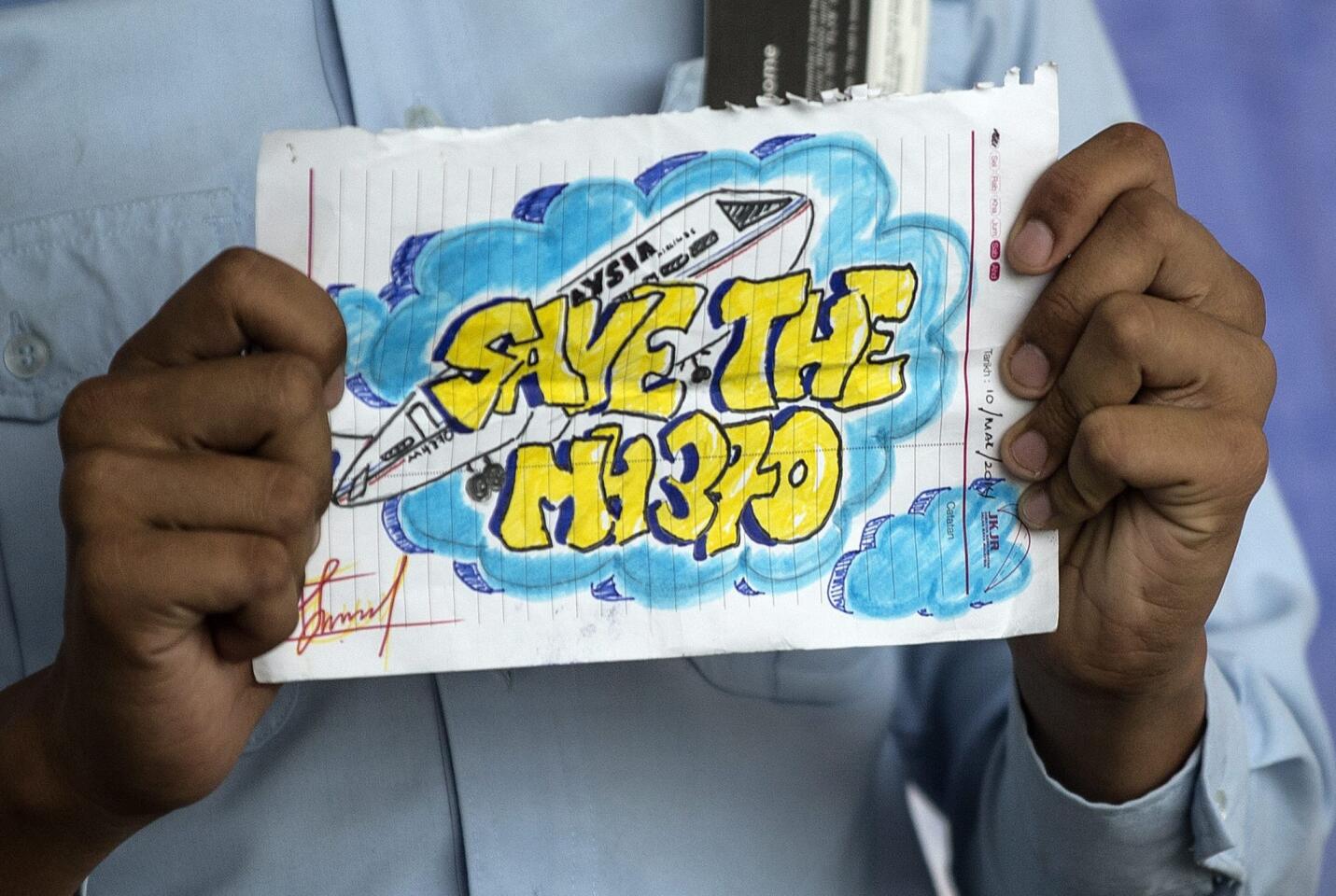A man holds a message for the missing Malaysian Airlines plane at Kuala Lumpur International Airport viewing gallery, Sepang, Selangor, Malaysia 19 March 2014.