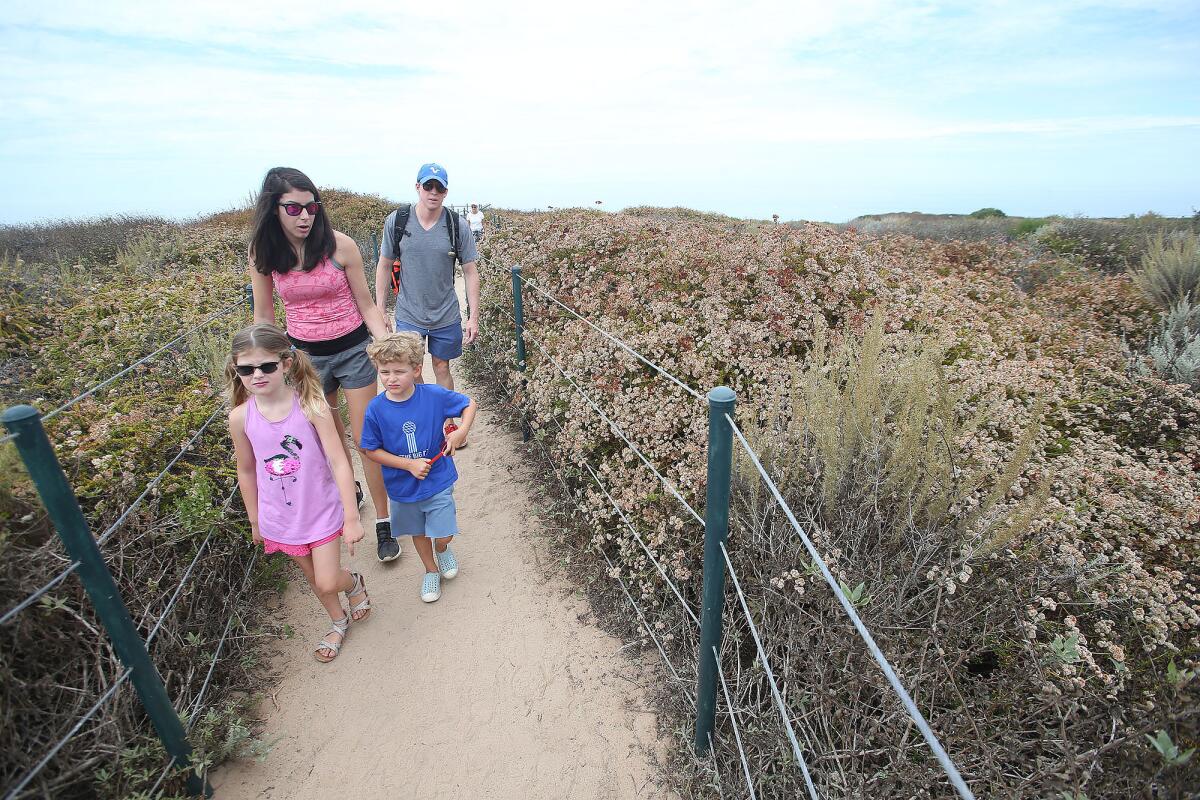 A family walks along a nature trail at the Dana Point Headlands.