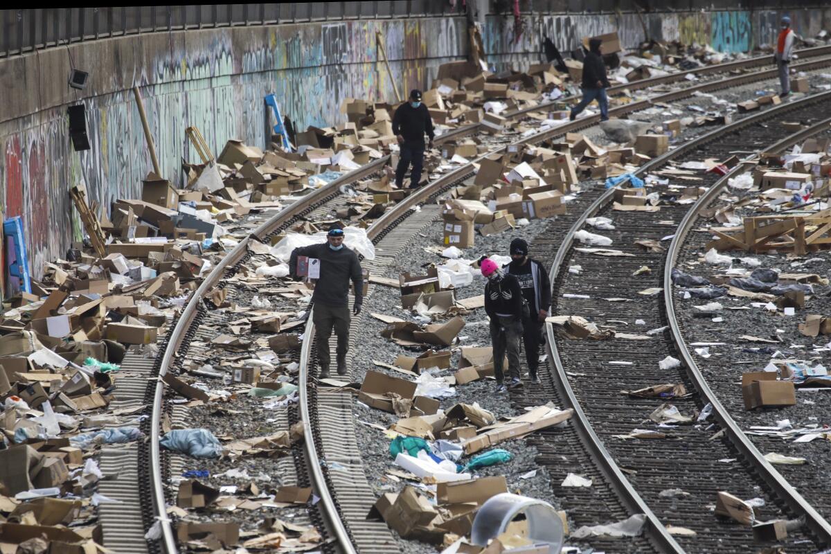 People walk among packages littering train tracks