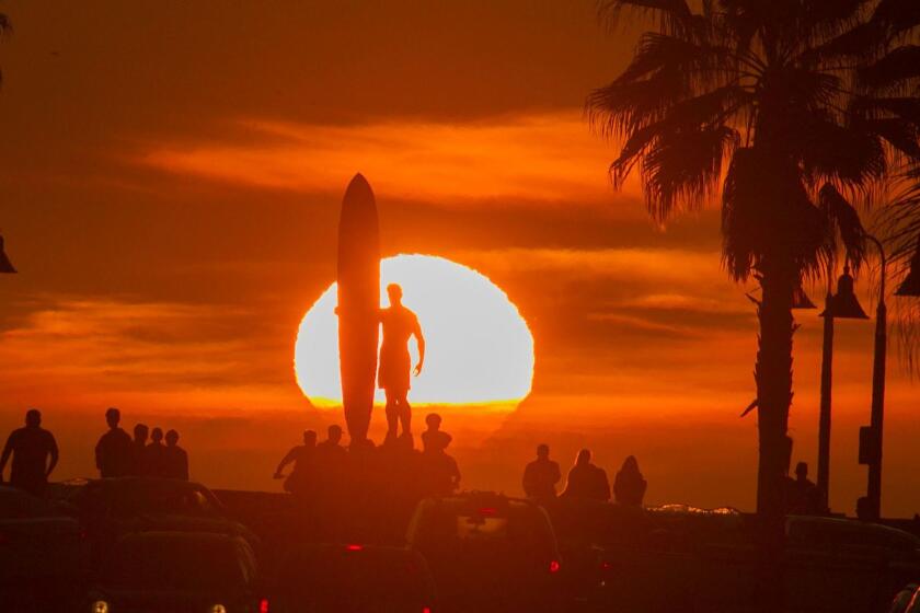 SAN DIEGO, CA-March 18: A sunset perfectly lined up with Palm Avenue in Imperial Beach and the "Spirit of Imperial Beach" statue on Saturday, March 18th, as people lined the seawall to watch the glowing disk sink in to the Pacific. JOHN GIBBINS / San Diego Union-Tribune)