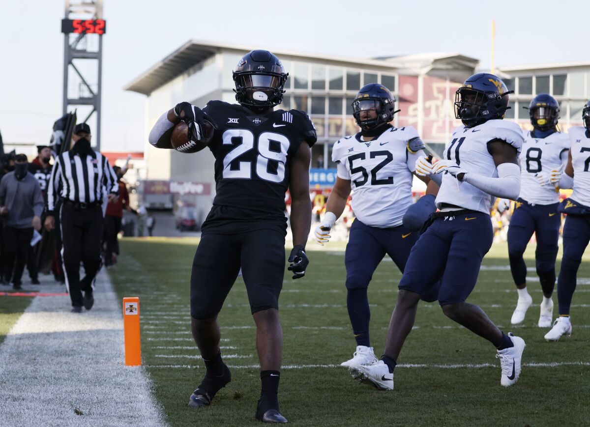 Iowa State running back Breece Hall, left, runs in a touchdown as West Virginia defensive lineman Jalen Thornton, center, and cornerback Nicktroy Fortune, right, are late to the play during the first half of an NCAA college football game, Saturday, Dec. 5, 2020, in Ames, Iowa. (AP Photo/Matthew Putney)