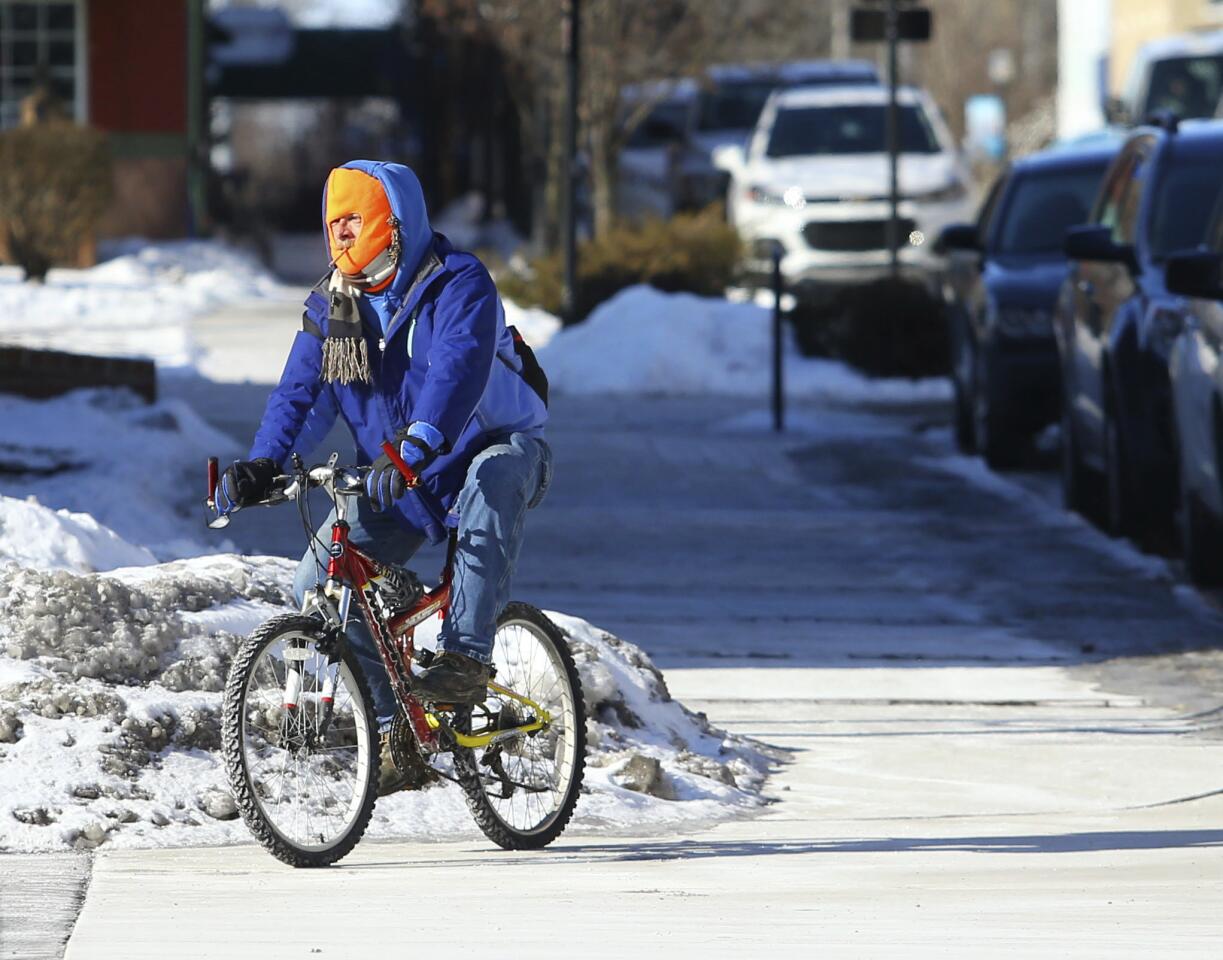 A bundled up bicyclist rides his bike toward the trolley stop in downtown Kokomo, Ind., Wednesday, Jan. 30, 2019 with temperatures reaching into the negative double digits. (Kelly Lafferty Gerber/Kokomo Tribune via AP)