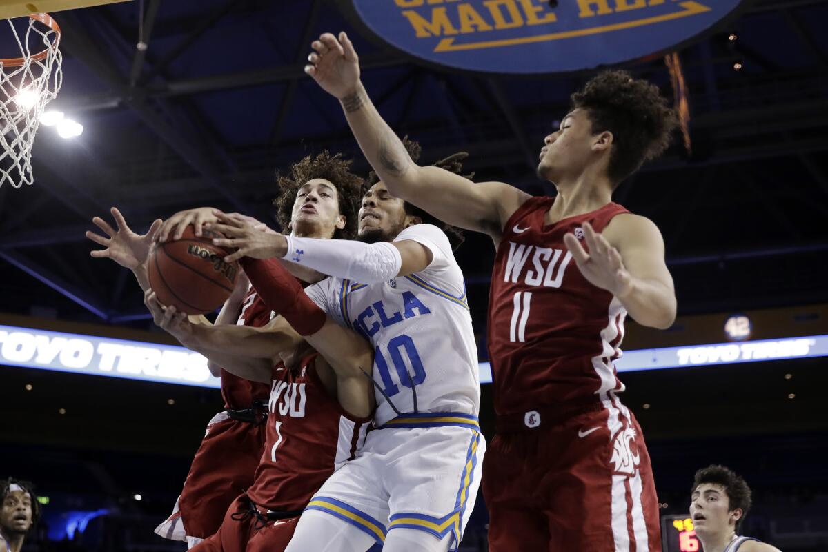 UCLA guard Tyger Campbell (10) battles with Washington State guard Jervae Robinson (1) and DJ Rodman (11) for a rebound during the first half of a game Feb. 13 at Pauley Pavilion.