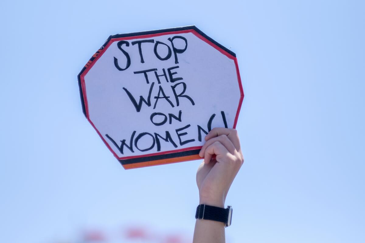 A sign says "Stop the war on women!" 
