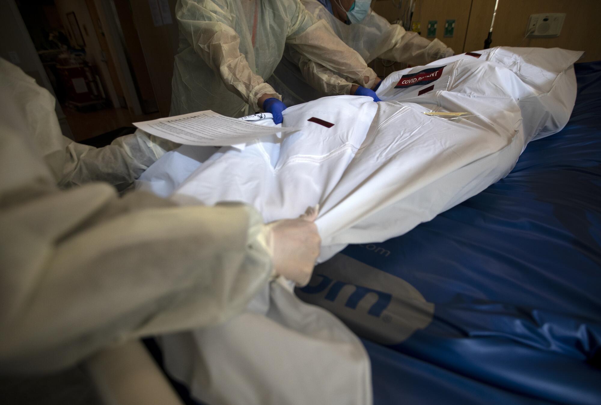A "covid patient" label and covid stickers have been placed on the white bag containing a deceased patient. 