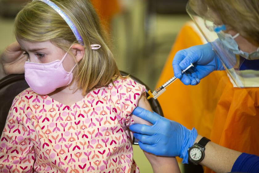 Rebecca Kellen, 7, looks away as she gets her COVID-19 booster at a vaccination clinic hosted by Los Angeles County Public Health at Balboa Sports Complex in Encino, Calif., on Saturday May 21, 2022. COVID-19 booster shots are now available for children ages 5-11 in Los Angeles County and LA County Public Health is encouraging parents to bring eligible children to vaccination sites to get boosted before summer vacation and holiday travel. (Alisha Jucevic/For The Times)