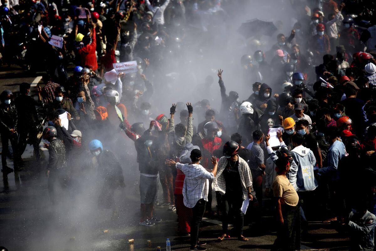 Protesters are sprayed by a police truck's water cannon in Naypyitaw, Myanmar. 