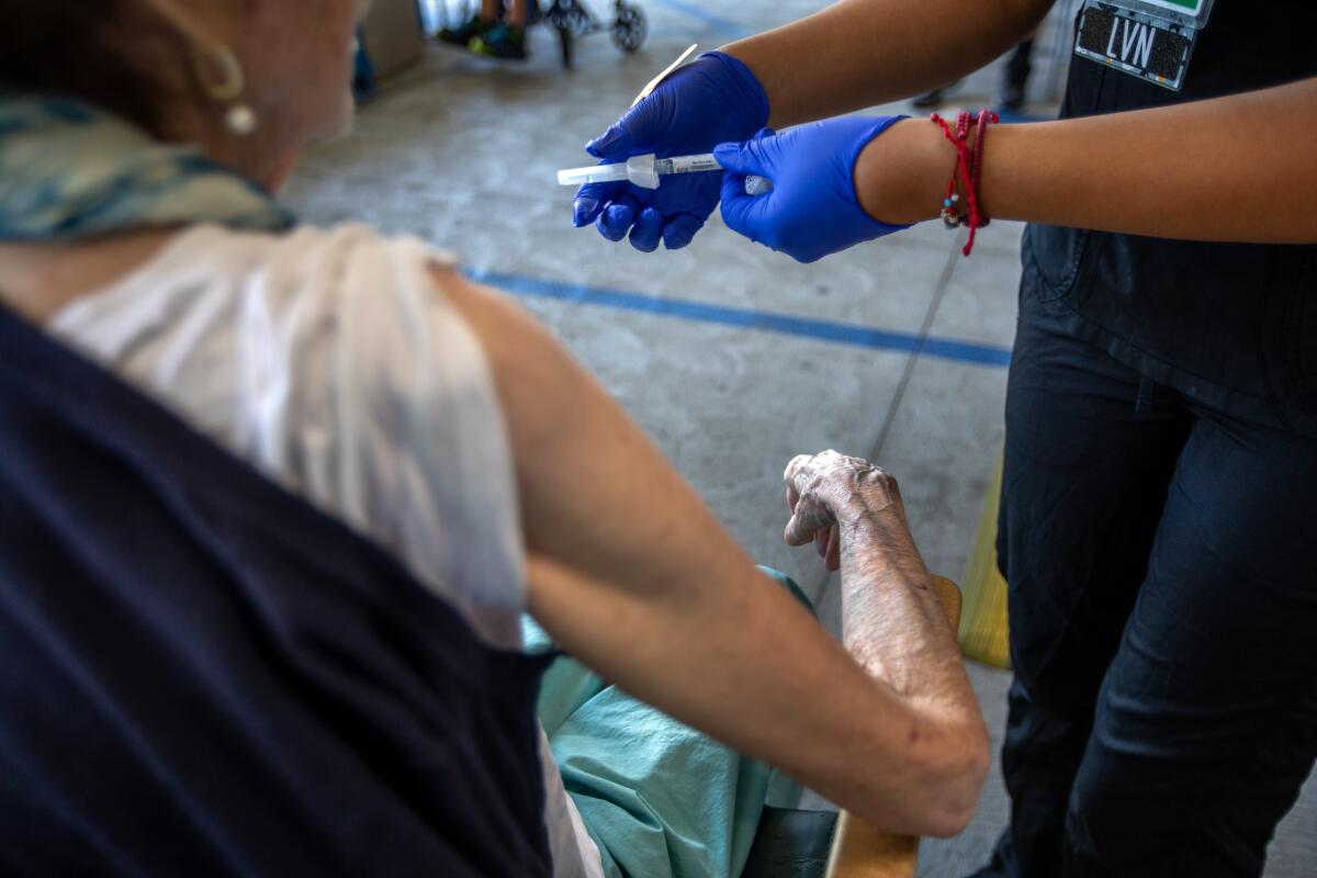 A woman in gloves prepares a vaccine for administration