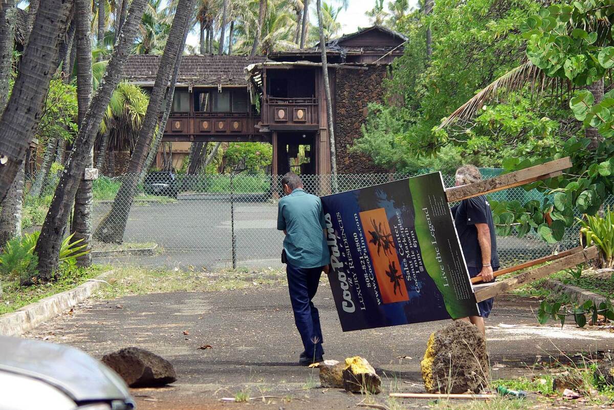 FILE - In this Sept. 13, 2007, file photo, workers move the Coco Palms Resort unit sales sign away from the Kuamoo Road side of the former resort in Wailua, Hawaii. The historic resort where Elvis Presley's character got married in the 1961 film "Blue Hawaii" will go up for auction at a foreclosure sale on Kauai this month. The Garden Island newspaper reported the abandoned Coco Palms Resort will be auctioned July 26, 2021, on the steps of the Fifth Circuit Courthouse in Lihue. (Dennis Fujimoto/The Garden Island via AP, File)
