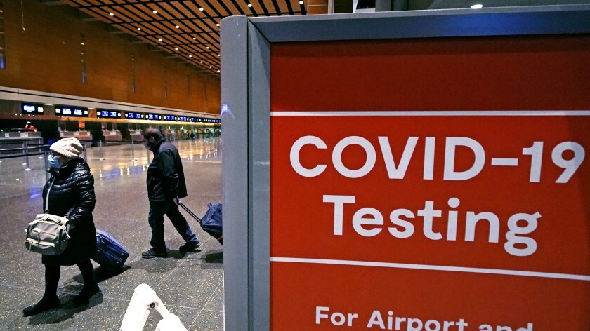 FILE - Travelers pass a sign near a COVID-19 testing site in Terminal E at Logan Airport, on Dec. 21, 2021, in Boston. A new AP-NORC poll shows that few Americans – just 15% – say they'll consider the pandemic over only when COVID-19 is largely eliminated. By contrast, 83% say they'll feel like the pandemic is over when it's largely a mild illness, like the seasonal flu. (AP Photo/Charles Krupa, File)