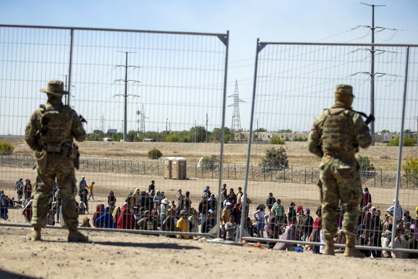 FILE - Migrants wait in line adjacent to the border fence under the watch of the Texas National Guard to enter into El Paso, Texas, Wednesday, May 10, 2023. U.S. authorities say an 8-year-old girl died Wednesday, May 17, in Border Patrol custody, a rare occurrence that comes as the agency struggles with overcrowding. The Border Patrol had 28,717 people in custody on May 10, the day before pandemic-related asylum restrictions expired, which was double from two weeks earlier, according to a court filing. (AP Photo/Andres Leighton, File)