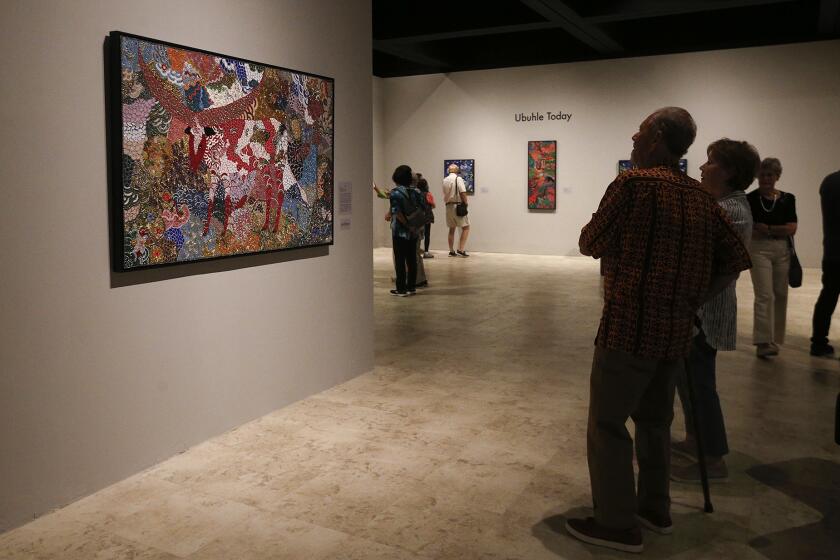 Guests admire the intricate micro bead work of "Dressed for the Dance by Zondlile Zondo at the Bowers Museum.