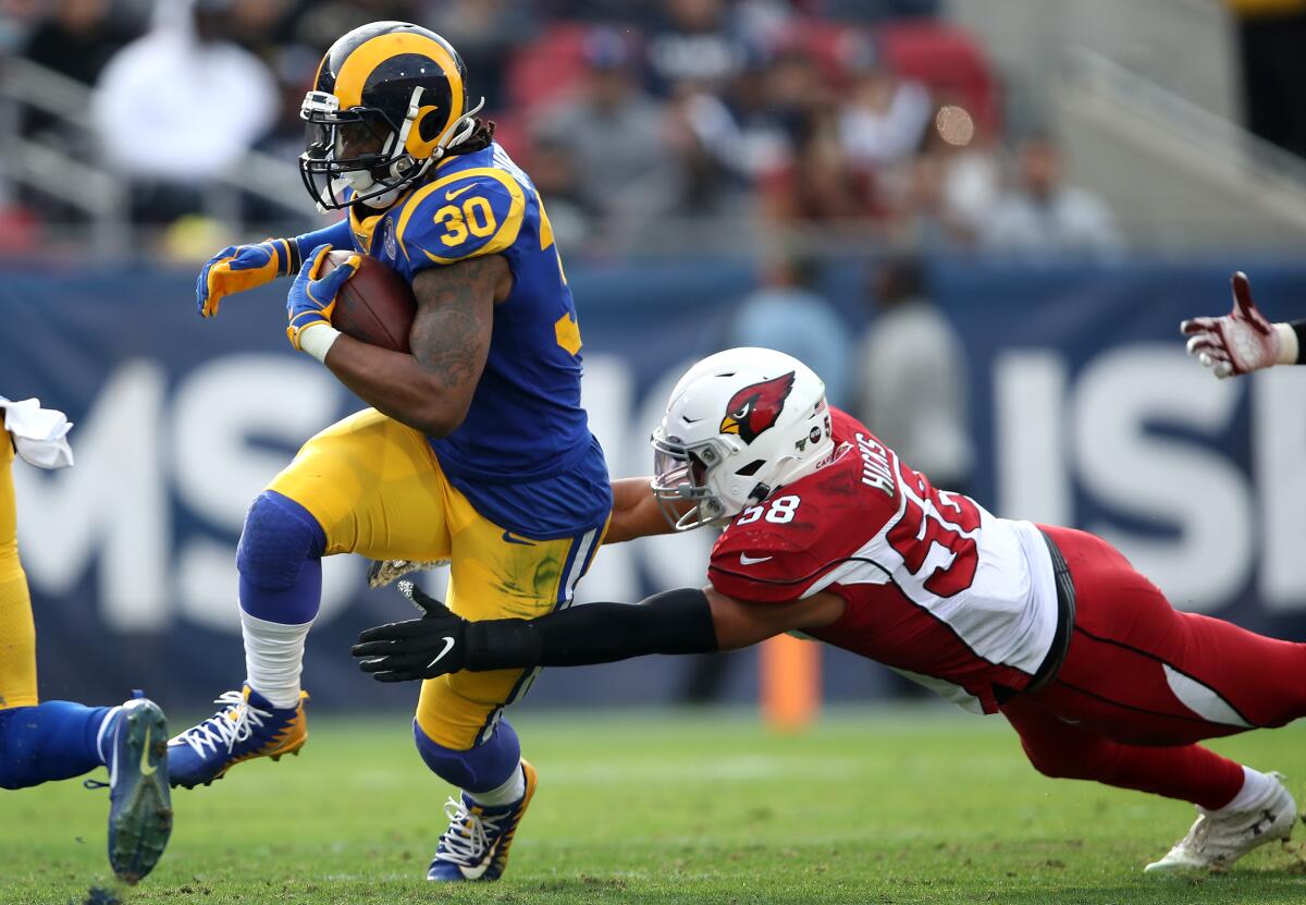 Rams running back Todd Gurley breaks the tackle of Arizona Cardinals defender Jordan Hicks during the first half at the Coliseum on Dec. 29, 2019.