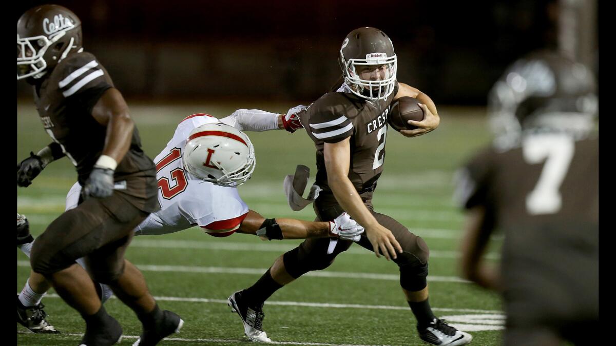 Crespi quarterback Hamish McClure eludes the grasp of Orange Lutheran linebacker T.J. Augustin in a game on Sept. 4, 2015.