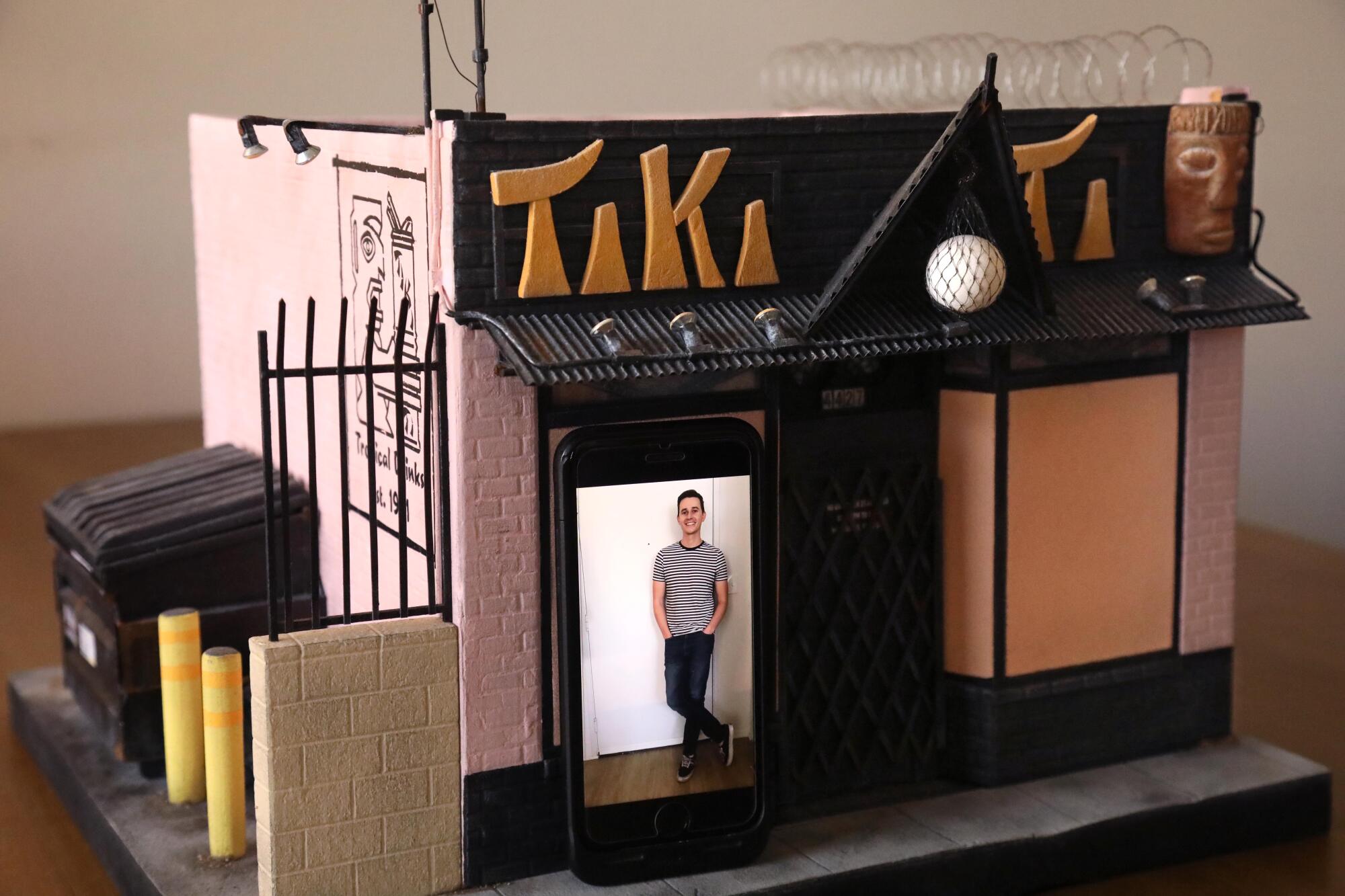  Kieran Wright, in an iPhone photo, seems to be in scale with his miniature creation of the Tiki-Ti bar.