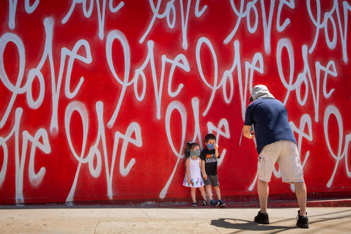 Tom Sean Foley pauses on a walk with his children to take a photo in front of the "Love Wall," a mural by artist Curtis Kulig, outside of Smashbox Studios in Culver City.