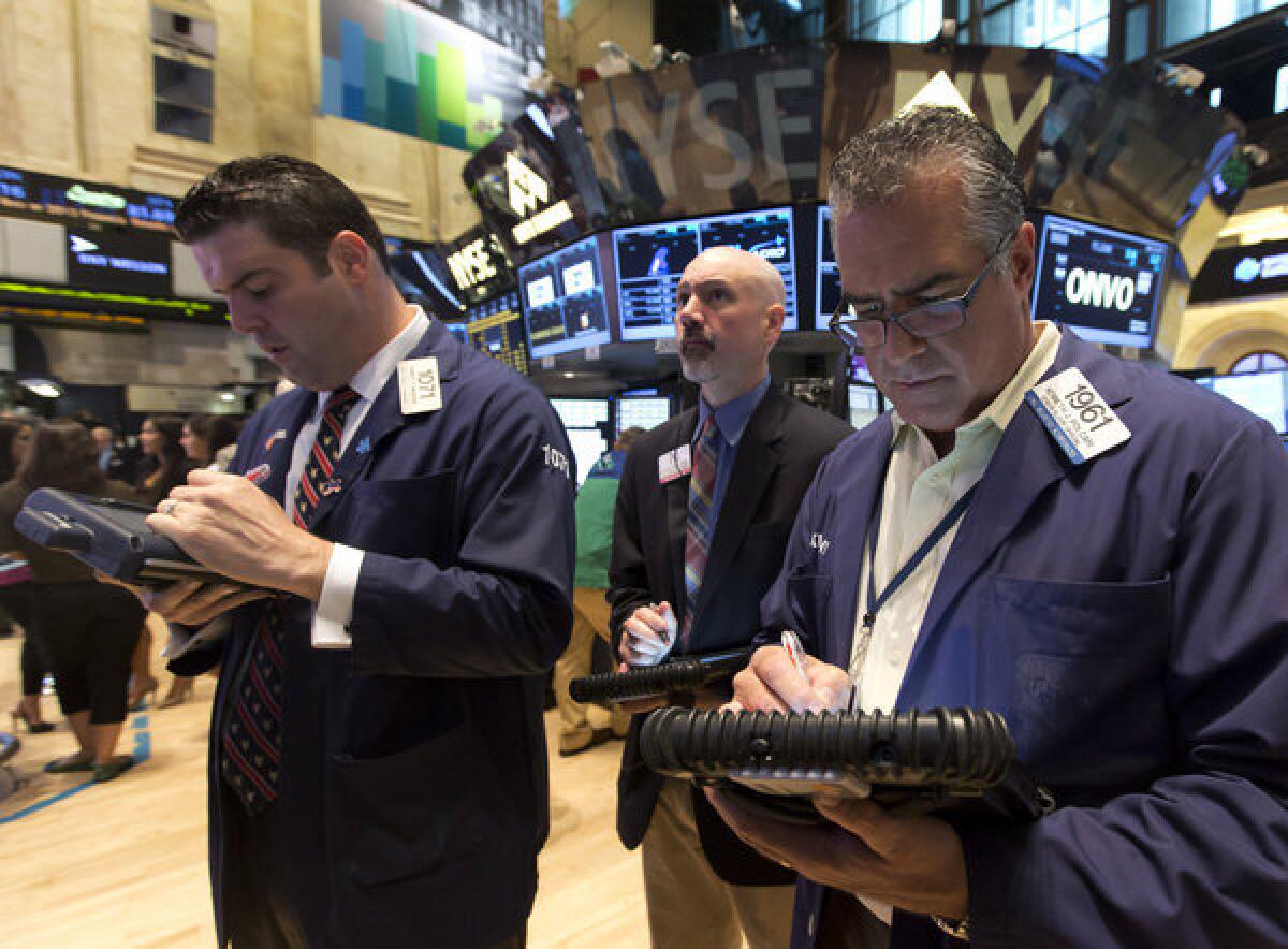 Kenneth Polcari, right, works with fellow traders on the floor of the New York Stock Exchange on Friday. The U.S. stock market rally that led to record highs Thursday has stalled. Major indexes were little changed in morning trading Friday.