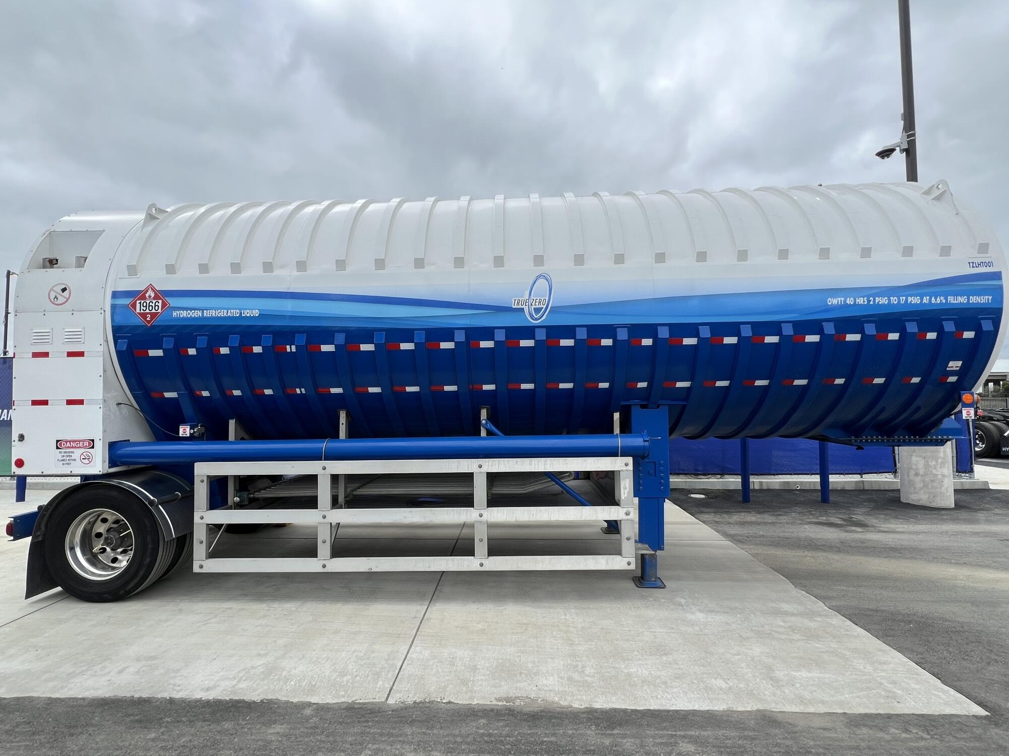 A blue and white tank for hydrogen fuel transport, on a wheeled trailer, at the Port of Oakland.