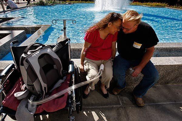 Tammy Lumpkins, who has received an artificial heart, spends a warm moment with her husband, Dale, near a fountain in front of the Keck Hospital of USC in Los Angeles. See full story