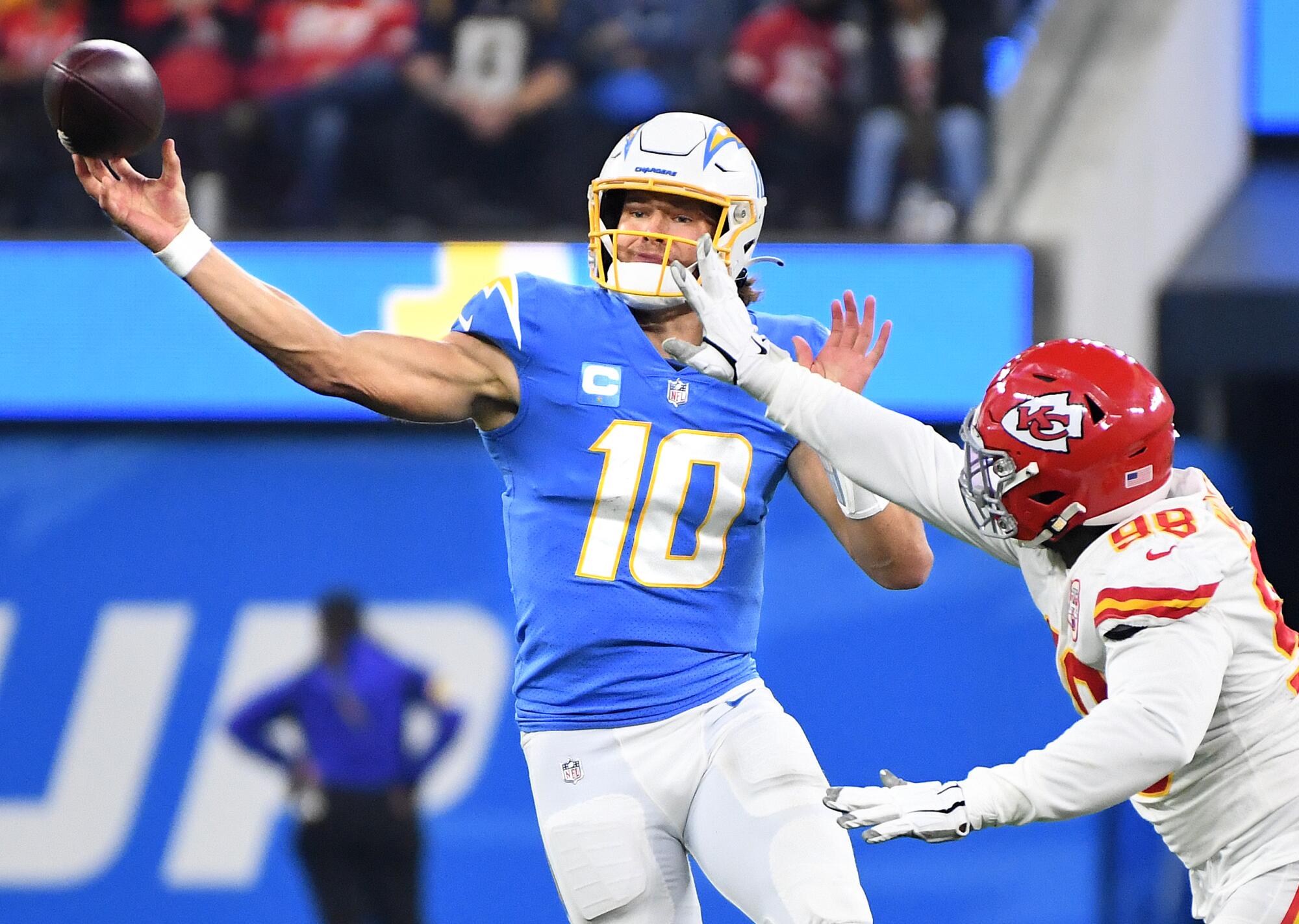 Chargers quarterback Justin Herbert delivers a pass despite pressure from a Chiefs defensive tackle Tershawn Wharton.
