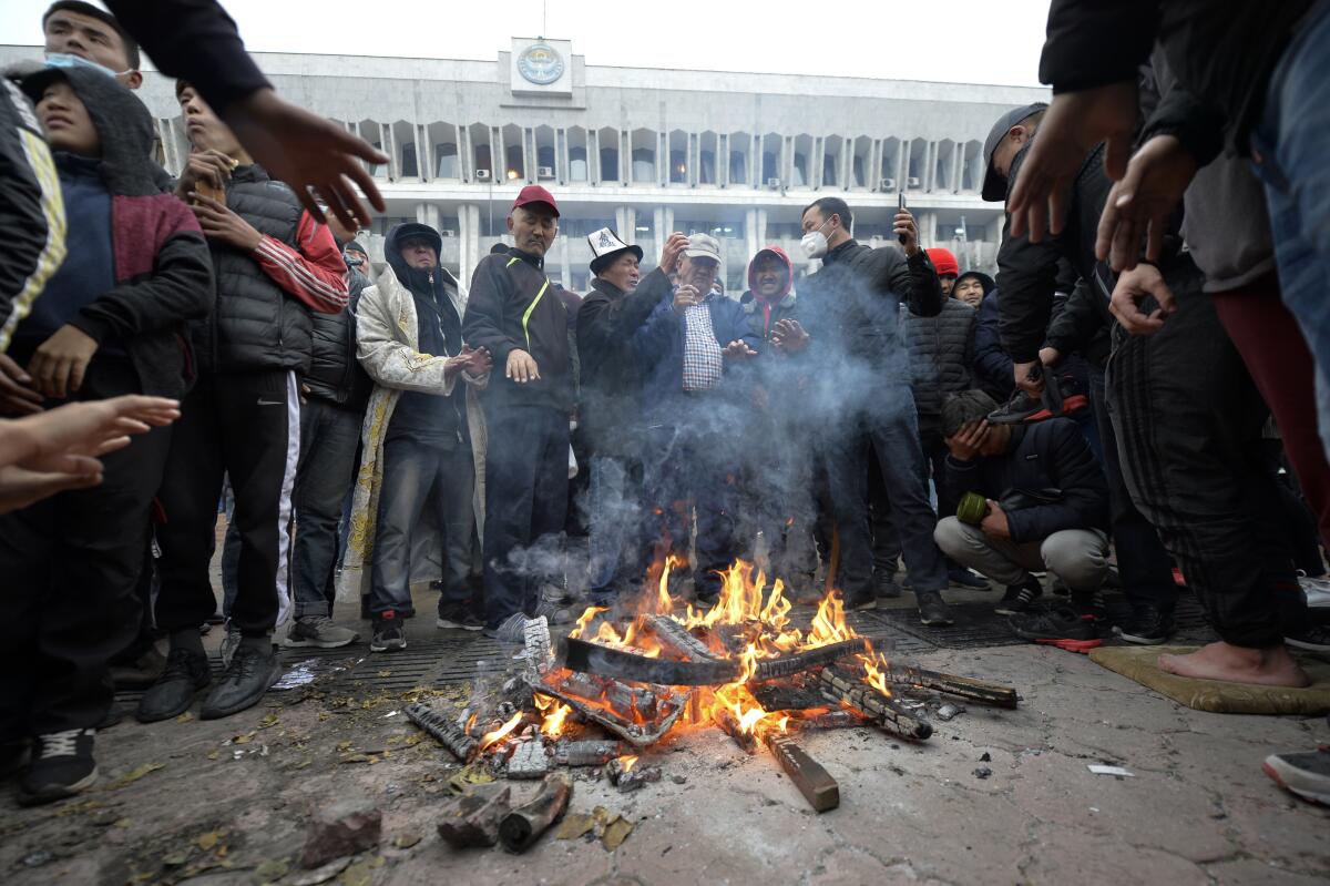 Protesters gather around a fire set in the street in front of the Kyrgyz government headquarters
