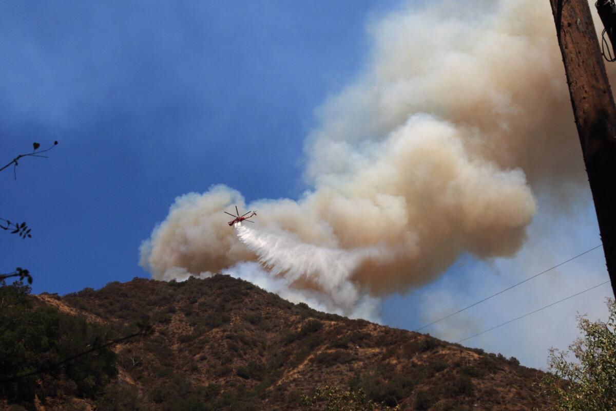 An Orange County Fire Authority helicopter makes a water drop on a brush fire in the Cleveland National Forest on Sept. 13. Forecasters say conditions will be ripe for brush fires through Thursday as a heat wave sweeps over the Southland.