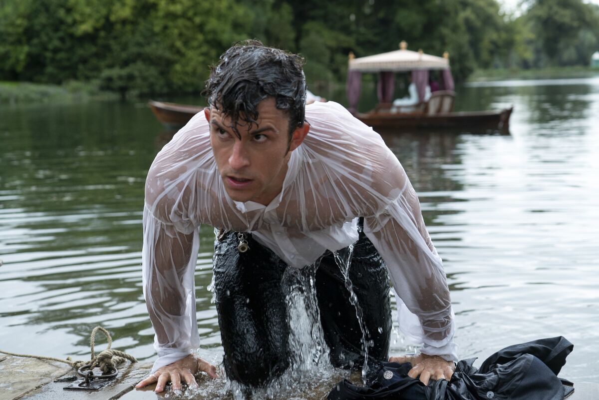 A man emerges from a pond soaking wet