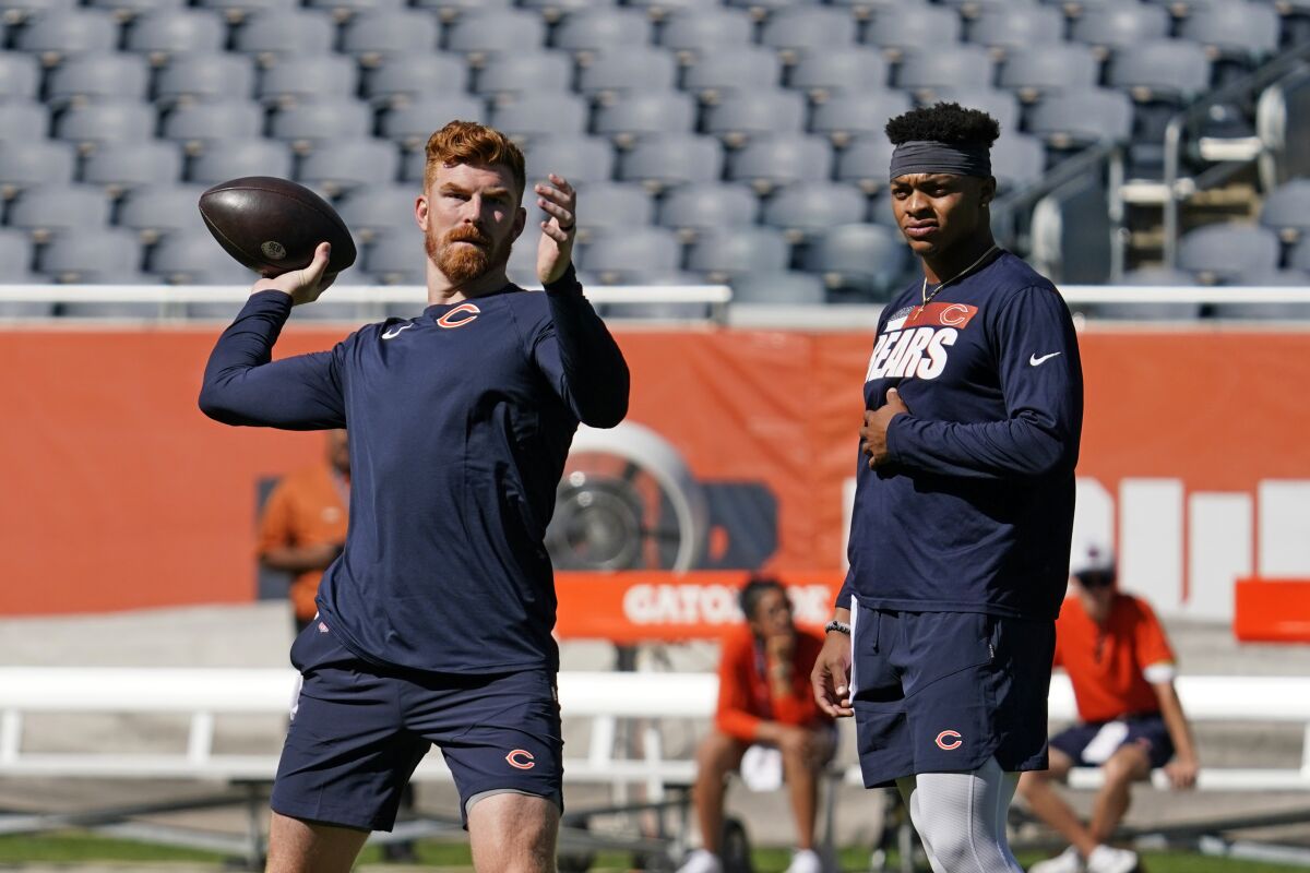 FILE - Chicago Bears quarterback Andy Dalton, left, looks to pass as quarterback Justin Fields watches as they warmup before an NFL preseason football game against the Miami Dolphins in Chicago, in this Saturday, Aug. 14, 2021, file photo. Justin Fields looked like he was ready to play during the preseason. But with veteran Andy Dalton penciled in as the No. 1 quarterback, it remains to be seen when the Chicago Bears' prized rookie will play again. Another question is how short a leash Dalton will be on with the former Ohio State star behind him. (AP Photo/Nam Y. Huh, File)